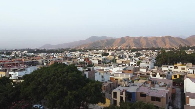 Panoramic view of city in Latin America at sunset, surrounded by hills in the neighborhood of Las Vi&ntilde;as de la Molina, Lima, Peru. Smooth upward movement with drone 