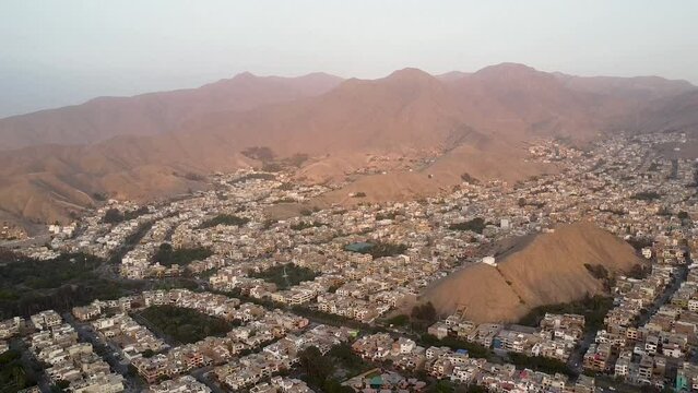 Panoramic of a town next to mountains during sunset in the Las Vi&ntilde;as neighborhood of La Molina, Lima, on the Peruvian coast. Smooth upward movement with drone.