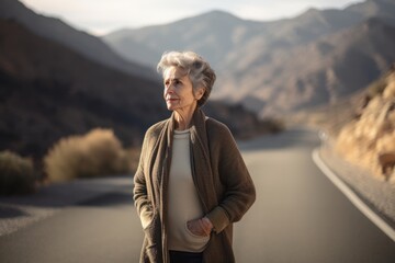 Fototapeta na wymiar Full-length portrait photography of a pleased woman in her 50s wearing a chic cardigan against a mountain pass or winding road background. Generative AI