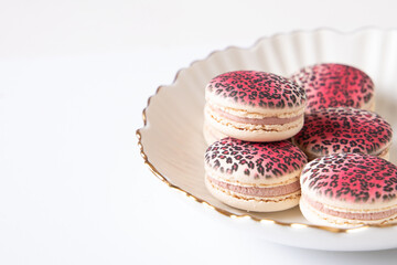 Sweet raspberry and vanilla macaroons with leopard design on plate
