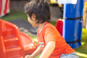 Fototapeta na wymiar Preschool child playing in a vibrant fun outdoor kindergarten yard