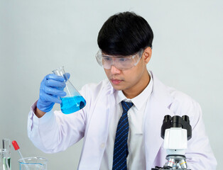 Fototapeta premium Asian male student scientist in reagent mixing laboratory In a science research laboratory with test tubes of various sizes and microscopes. on the table in laboratory chemistry lab white background.
