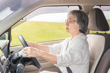 渋滞でイライラする自動車を運転する高齢者ドライバーの女性
