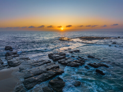 Aerial sunrise seascape with the sun, high tide and rock platform