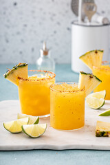 Pineapple margarita cocktail in glasses with tajin rim