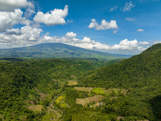 Fototapeta premium Aerial view of mountain slopes with rainforest and a mountain valley with farmland. Negros, Philippines