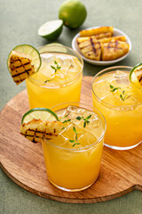 Grilled pineapple margarita garnished with lime wedges