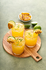 Grilled pineapple margarita garnished with lime wedges