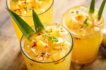 Grilled pineapple cocktail in tall glasses garnished with pineapple leaves