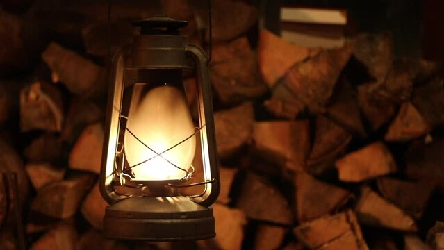 Dangling old kerosine lamp next to a pile of chopped wood, Gas lantern with burning light, copy space