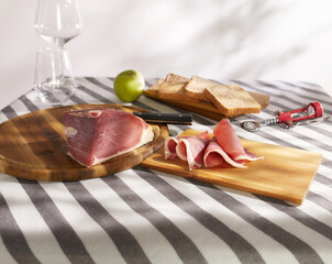 sliced prosciutto on a wooden board. pork ham on a light background. composition meat delicacy and...