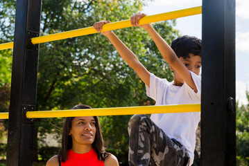 Mother and son enjoying playing at the playground in the park.