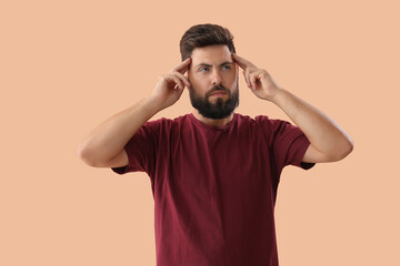 Thoughtful young bearded man on beige background