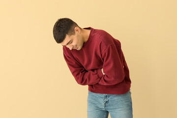 Young man with appendicitis on beige background