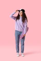 Teenage girl in cap with skateboard on pink background