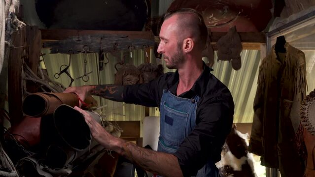 4K, Tall man was handmade by leather craftsman, was standing picking up roll hides that had been arranged in moisture-proof hide room do not let mold on animal skins, before being made into product.