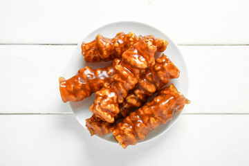 Plate with tasty churchkhela on light wooden background