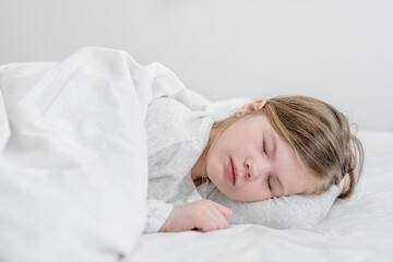 Cute little girl sleeps on the bed at home
