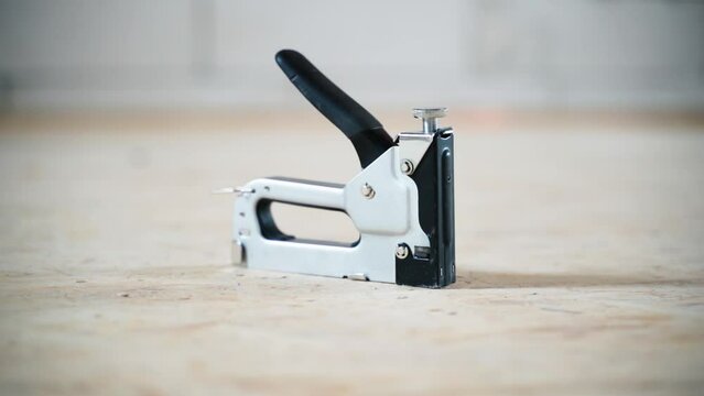 Gray construction stapler made of metal, close-up on a blurred background. Smooth camera movement
