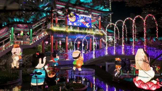 Landscape view of a public park decorated with Chinese lanterns at a nighttime lantern show as visitors are seen inside the Wong Tai Sin temple during the Mid-Autumn Festival (Mooncake Festival).