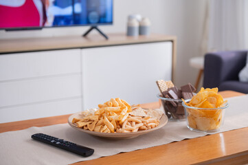 Snack on wooden table with television on background