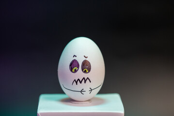 Animated egg with drawings of different faces and expressions mounted on a column in a large photograph