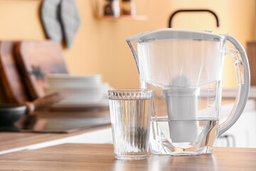 Modern filter jug and glass of water on kitchen counter