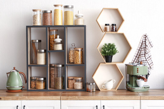 Shelves with jars of different food on kitchen counter near white wall - Powered by Adobe