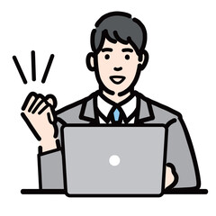 ラップトップの前で笑顔でガッツポーズをしているスーツを着た若い男性
