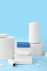 Podiums with thread spools and buttons on blue background