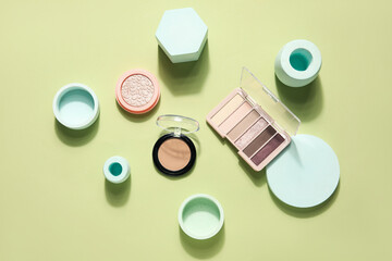 Eyeshadows with powder, highlighter and podiums on green background