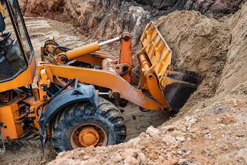 Powerful wheel loader or bulldozer working on a quarry or construction site. Close-up of...