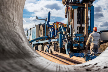 Pipes for a well close-up. Powerful drilling rig against a cloudy sky. Drilling of deep wells....