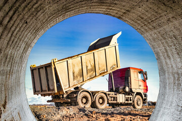 Dump truck with a raised body at a construction site. The process of transportation and unloading...