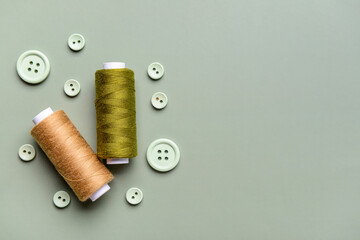 Composition with thread spools and buttons on grey background