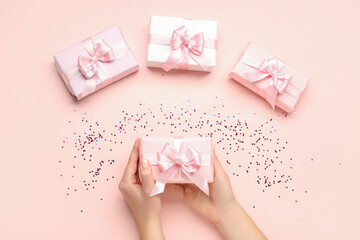 Composition with female hands holding gift box on pink background