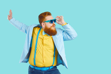 Cool cheerful bearded fat man in colorful stylish clothes and sunglasses is having fun and enjoying...