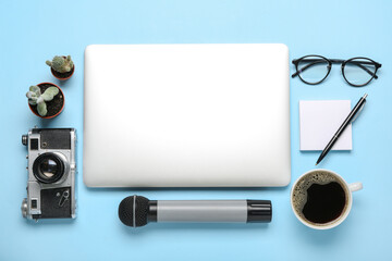 Laptop with photo camera, microphone, cup of coffee and sticky notes on blue background