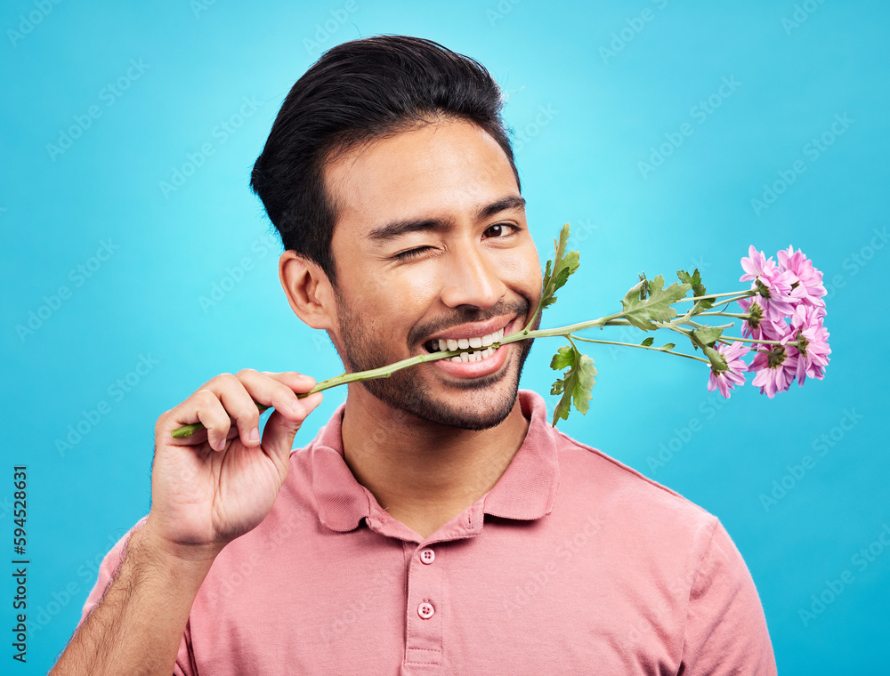 Wall mural Teeth, flower and wink with portrait of man in studio for celebration, gift and romance. Funny, goofy and present with male isolated on blue background for flirting, smile and valentines day mockup