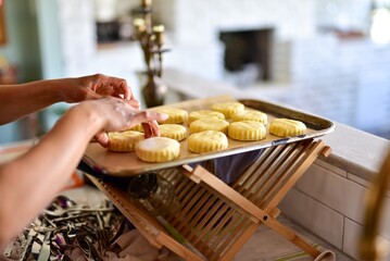 woman neatly placing fresh round cut biscuit dough on a baking sheet