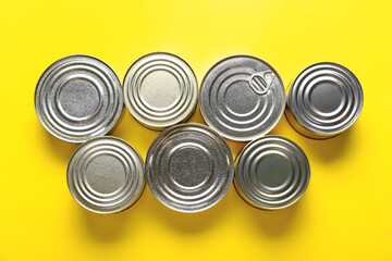 Assortment of tin cans with fish on yellow background