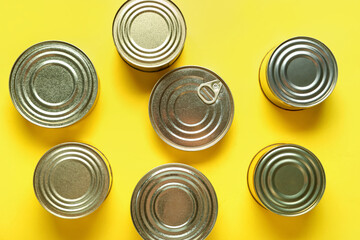 Assortment of tin cans with fish on yellow background