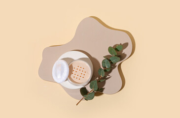 Decorative plaster podiums with powder and eucalyptus branch on beige background