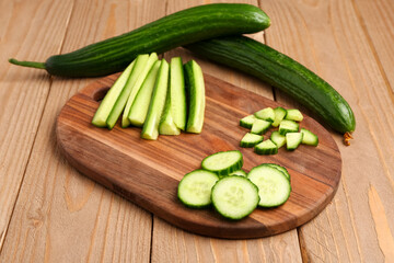 Board with fresh cut cucumber on wooden background