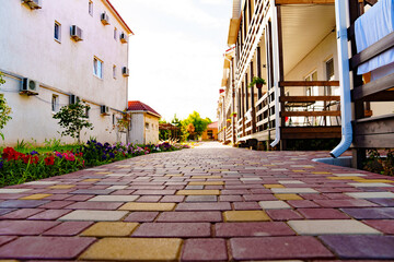 A tiled path near the two-story residential building of the guest house. 