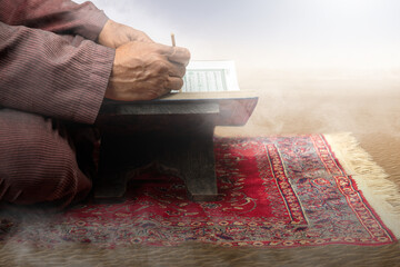 Muslim man sitting and reading the Quran on the prayer rug