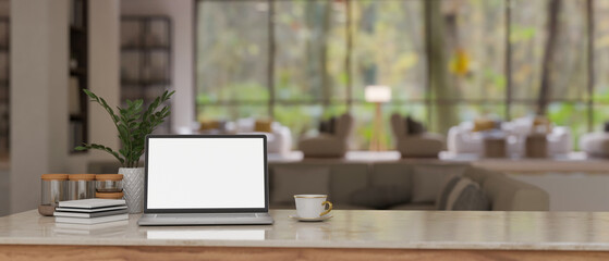 Workspace with laptop mockup on a table over blurred background of a modern lounge with sofa.