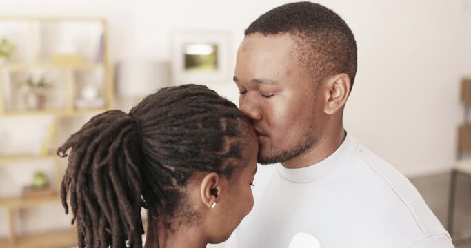 Love, forehead kiss and relax black couple dancing, bonding and enjoy marriage quality time together in living room. Home peace, slow dance and romantic man, woman or African people with affection