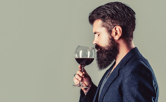 Glass of red wine in his hands. Sommelier, degustator with glass of wine, winery, male winemaker. Beard man, bearded, sommelier tasting red wine