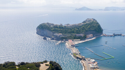 Aerial view of the island of Nisida. It is located in Naples, Italy. Nisida is a volcanic islet of the Flegrean Islands archipelago. It is connected to the city by a long pier. - obrazy, fototapety, plakaty